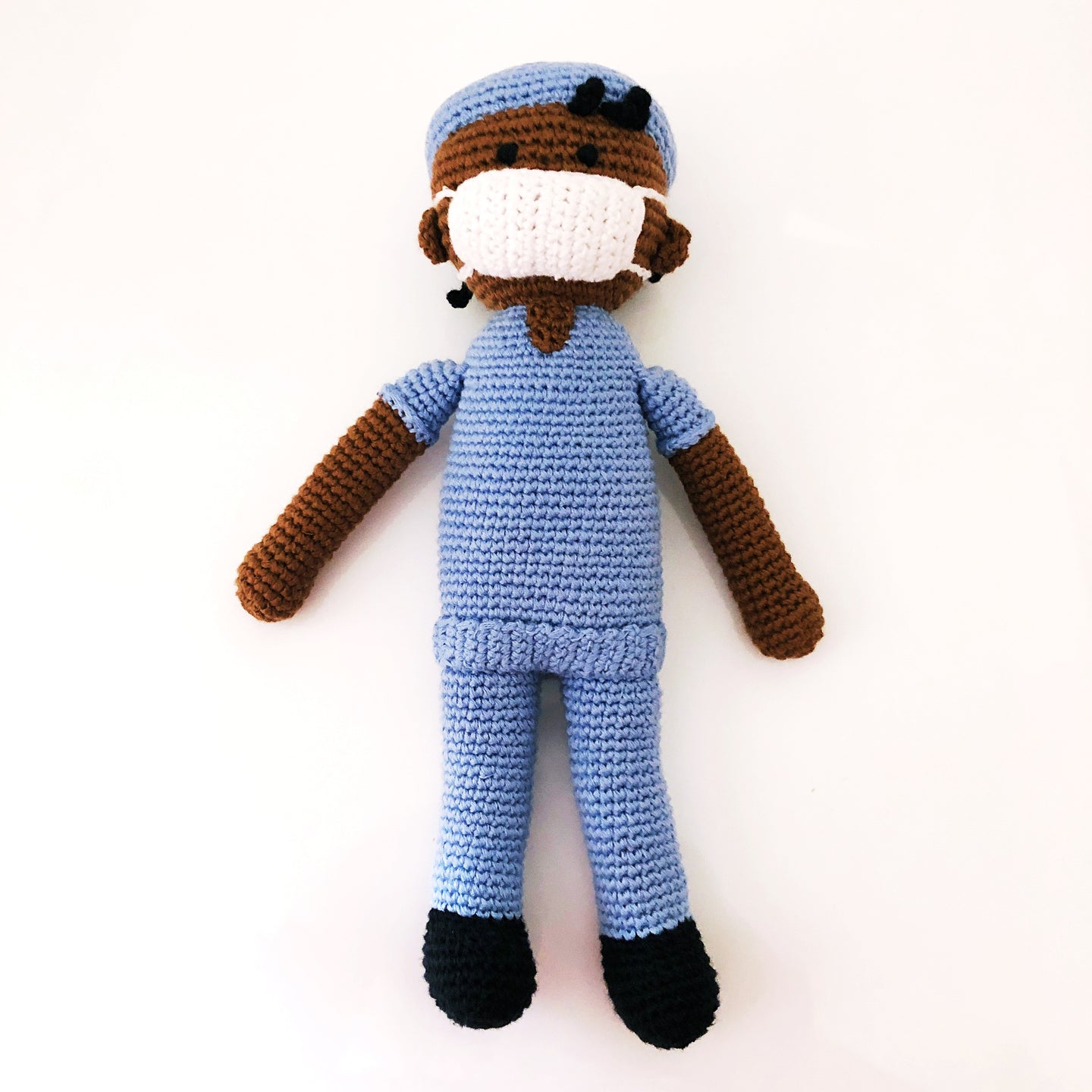 Dark-skinned doctor doll in blue scrubs and white mask